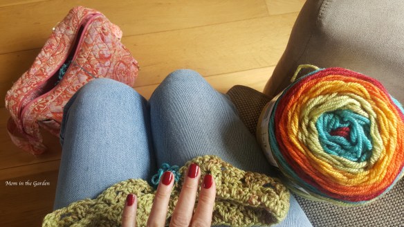 fingers with red nailpolish, rainbow colored yarn 